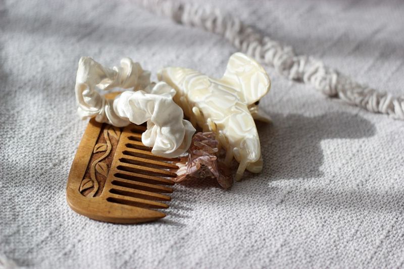 Satin scrunchies and a claw clip resting on a wooden comb